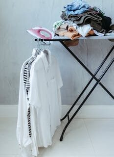 A neatly organized ironing board with clothes and an iron in a bright minimalist room.