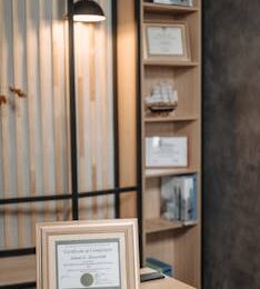 Stylish office interior featuring a framed diploma, modern desk, and elegant lighting.